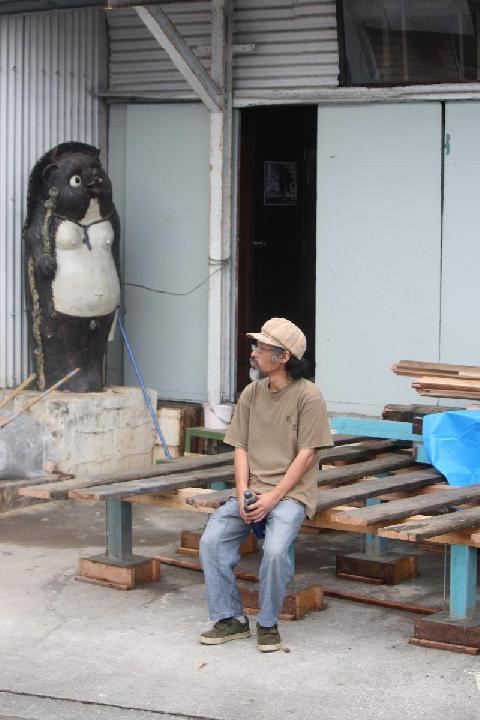 狸の像と座る人物