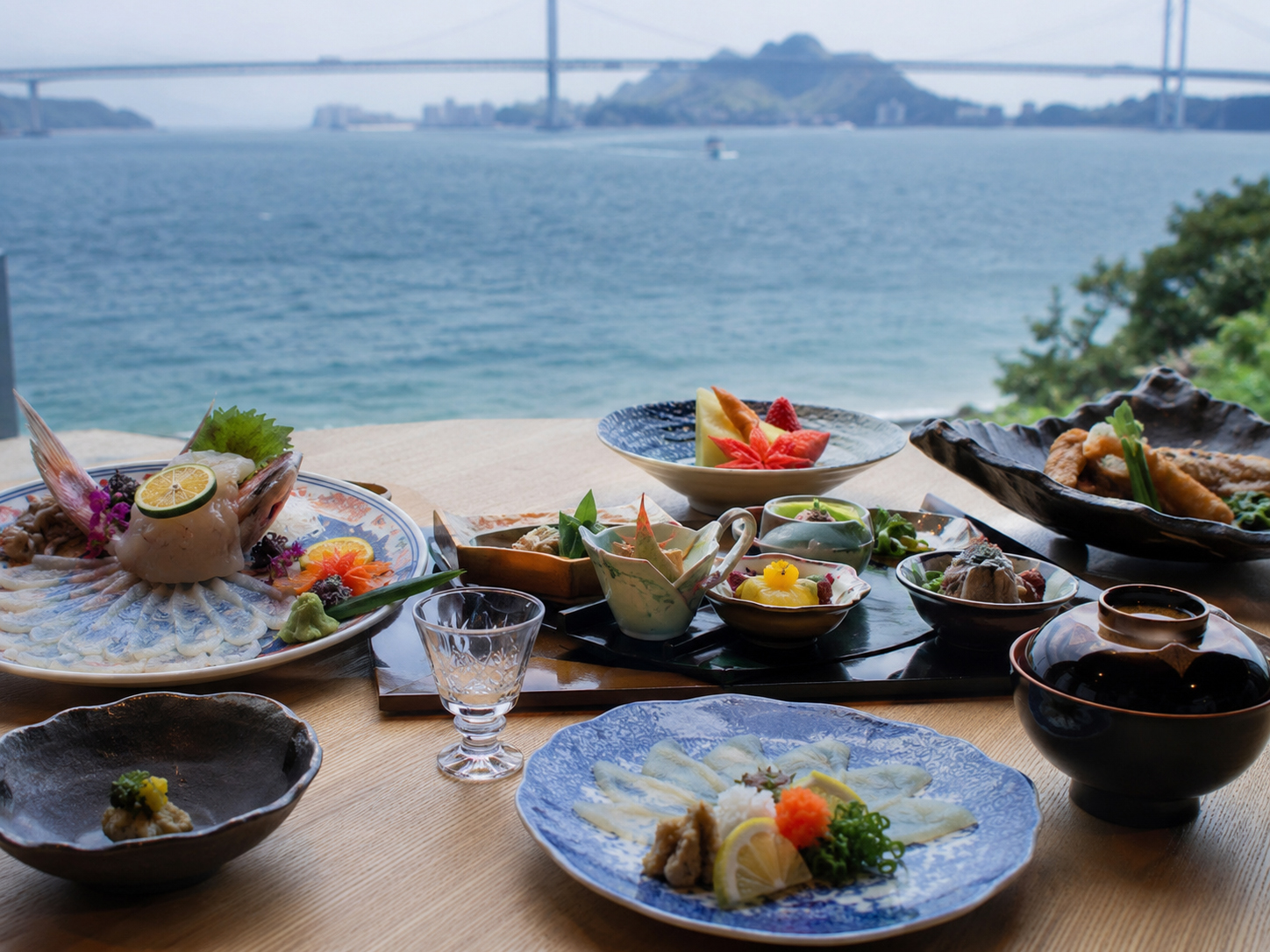 関門海峡を思わせる山口の食卓。ふく刺し、瓦そば、岩国寿司、やきとり、海鮮が並ぶ。